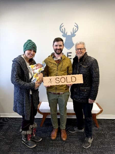Clients of The Hittner Group holding a wooden SOLD sign after their home sold